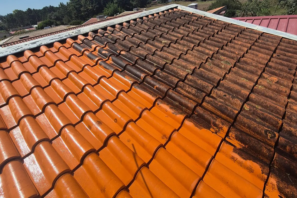 O mesmo telhado de telha em limpeza, parte limpa laranja em baixo à esquerda, parte ainda escura junto à cumeeira